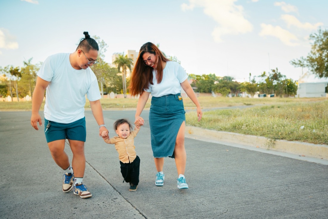 Pai, mãe e filho caminhando de mãos dadas ao ar livre